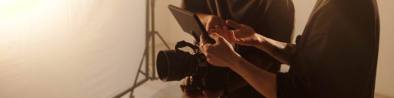 Camera operator adjusting a monitor on a film camera in a studio